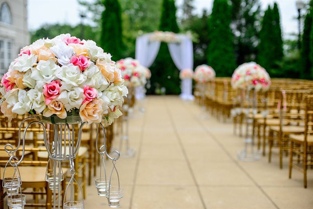 A wedding aisle lined with roses, leading to a draped floral arch