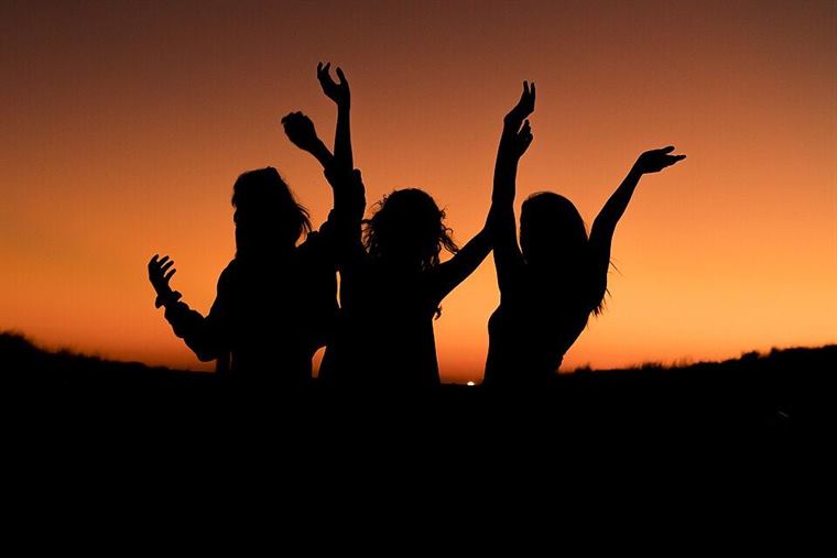 Friends celebrating against an orange sunset