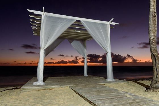 A white wedding pavilion on the beach at dusk