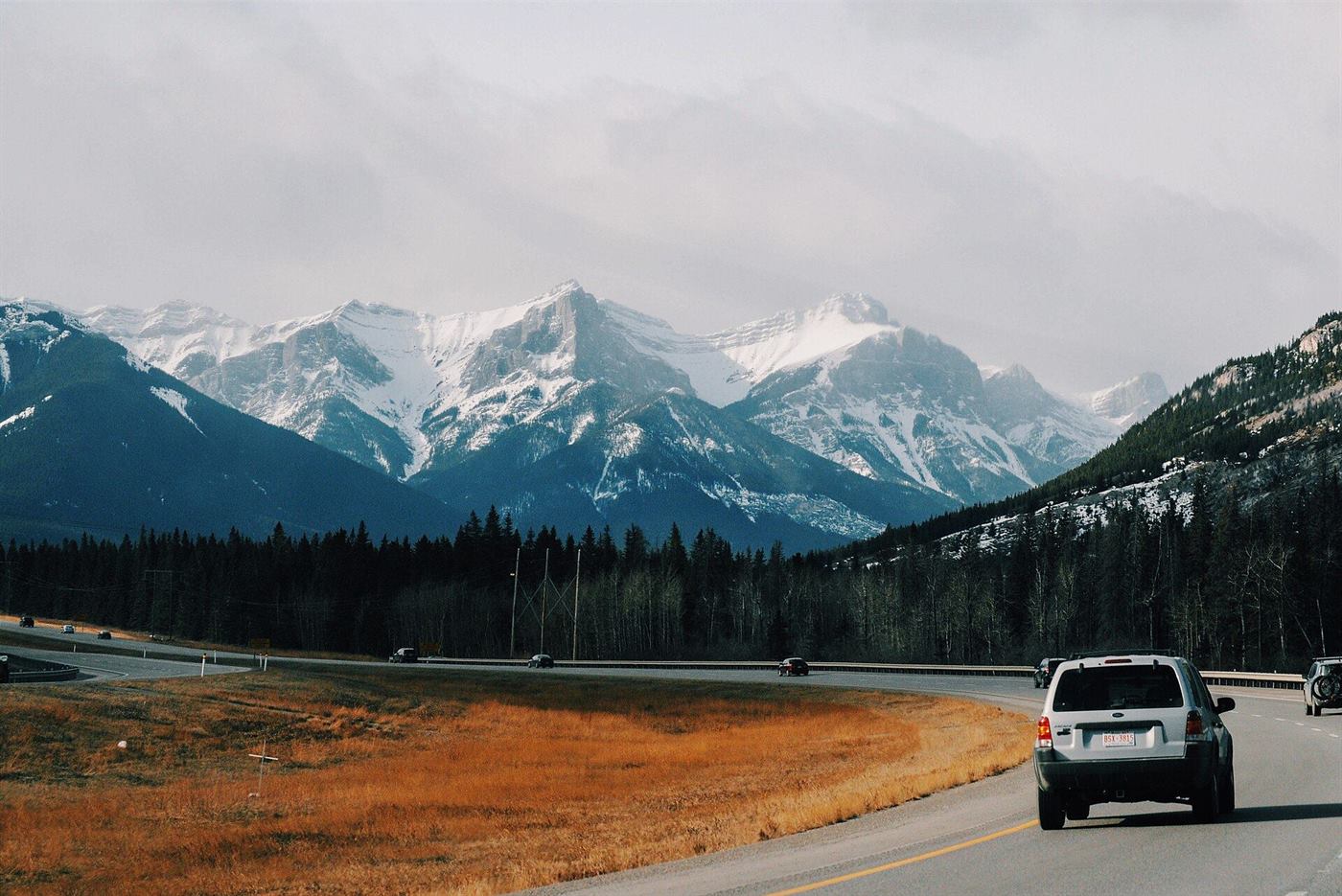 An SUV on a highway below snow-capped mountains