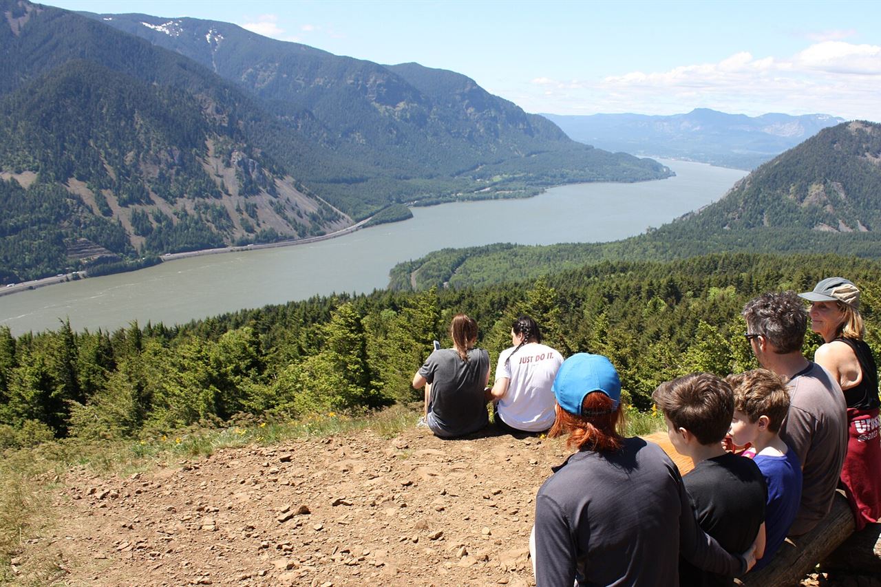 A family resting at a mountain viewpoint above a wide river valley