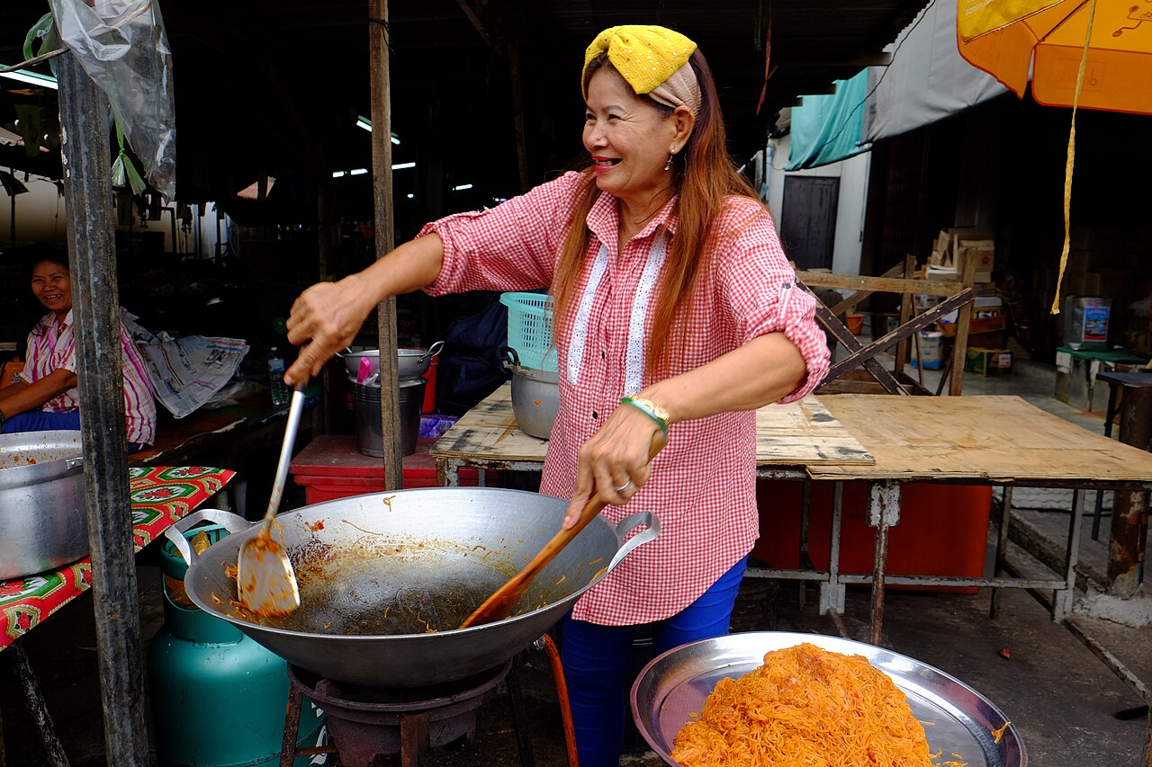 A street-food vendor cooking at her wok in Rayong, Thailand