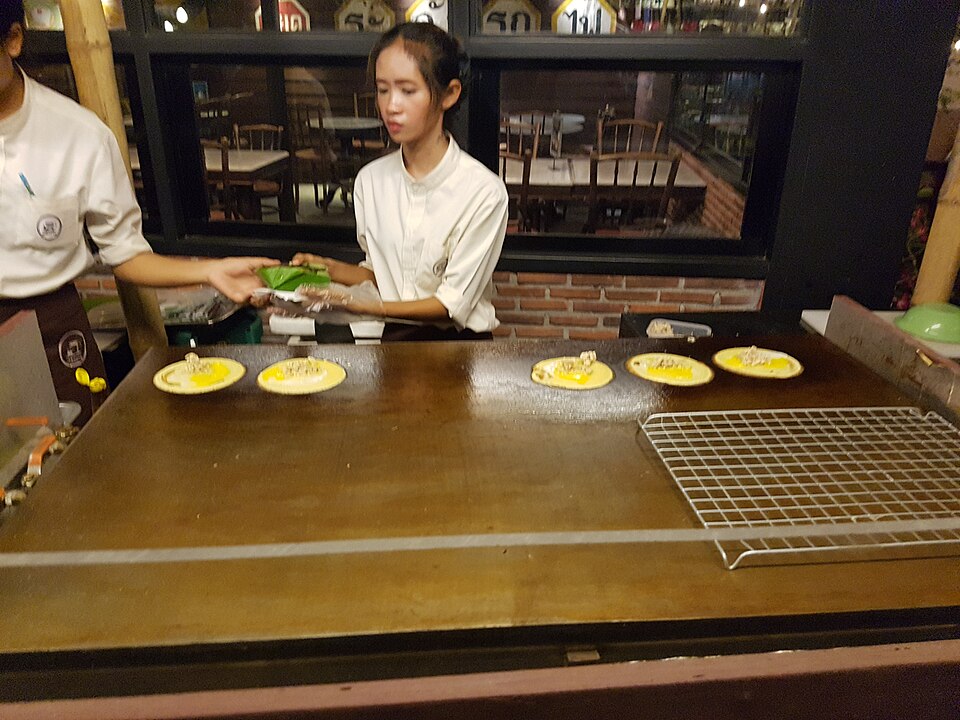 A street-food cook making Thai pancakes on a griddle in Hua Hin