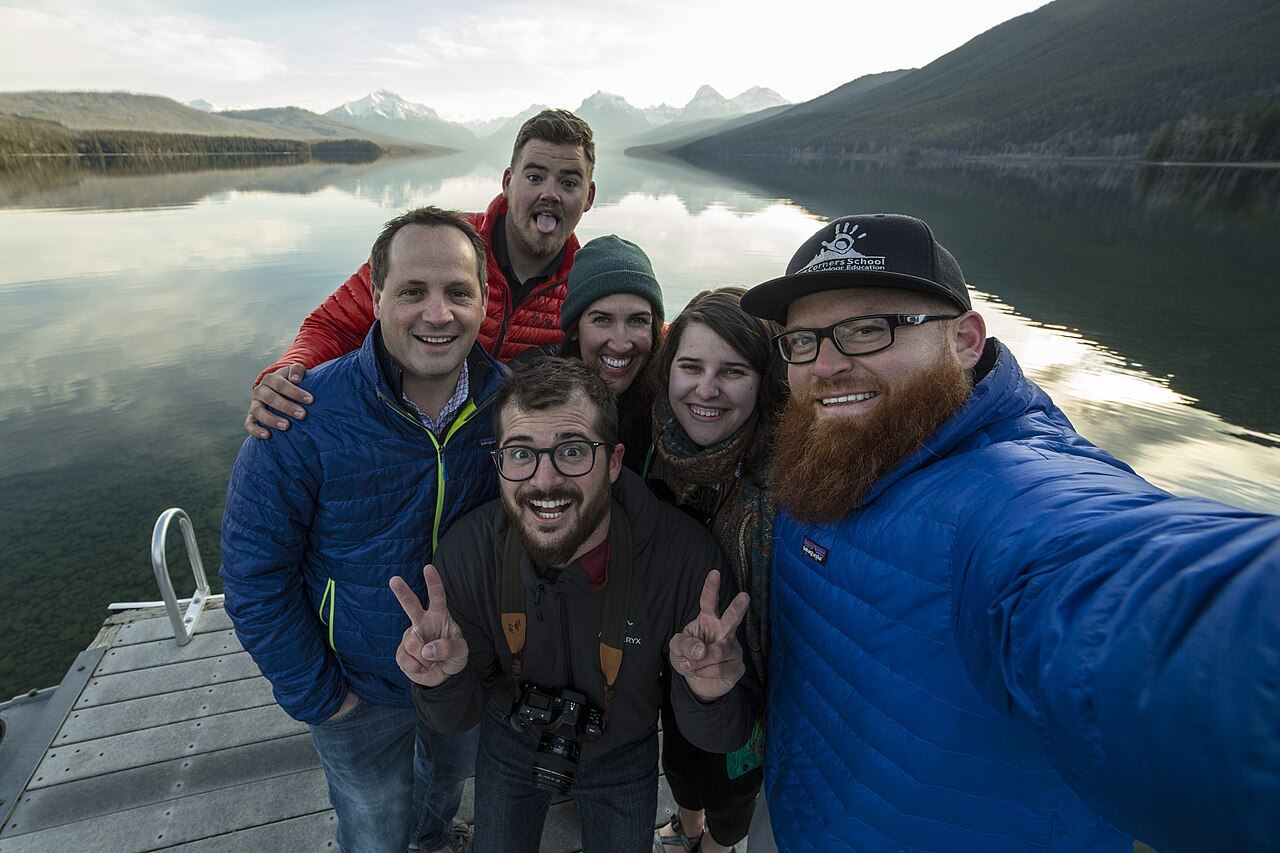 Friends taking a group selfie by a mountain lake