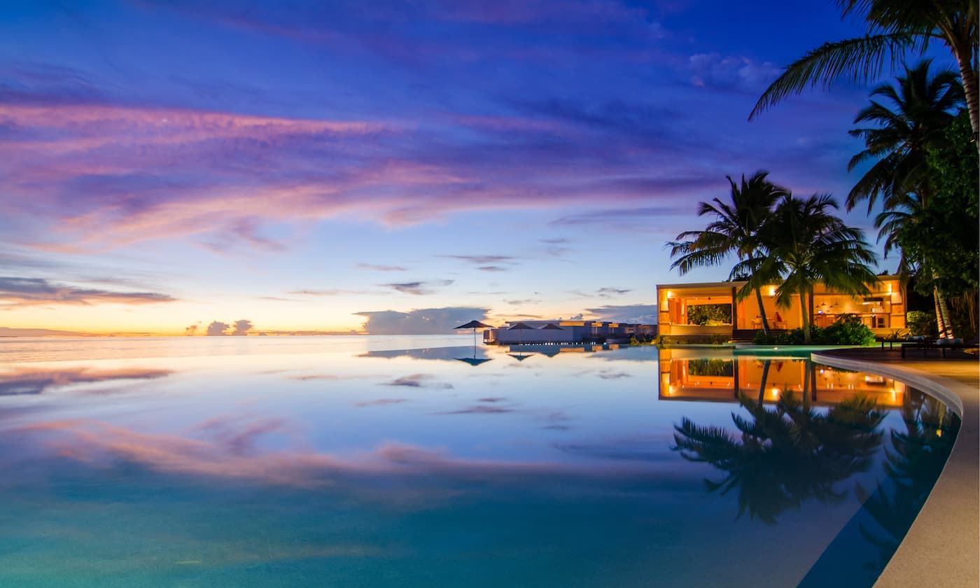 A resort pool beside the sea in the Maldives at sunset