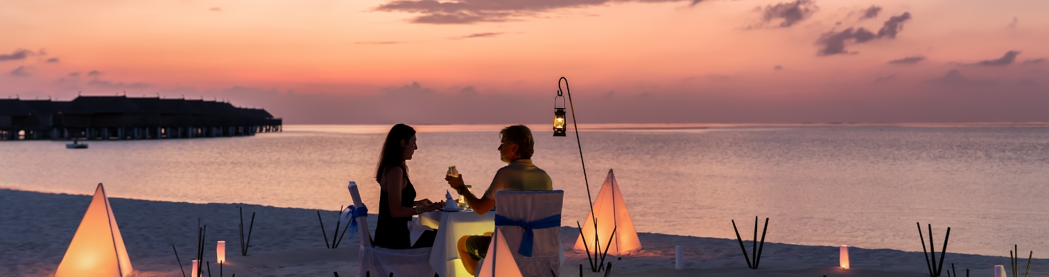 A candlelit dinner for two on a Maldives beach at dusk