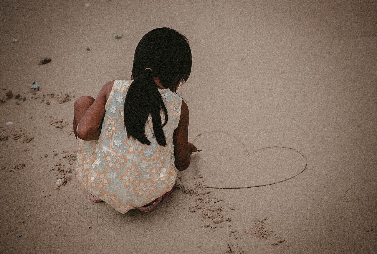 A girl drawing a heart in the sand