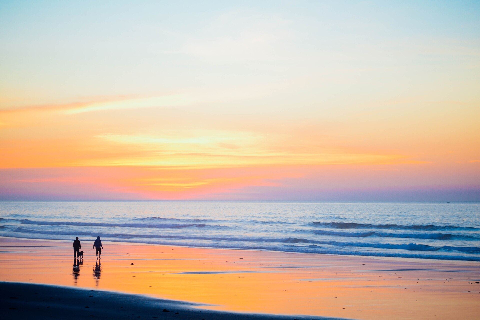 A family walking along the shore at sunset