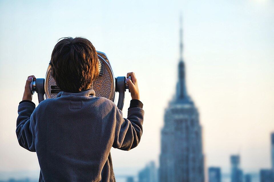 A child looking through a viewing binocular at a city