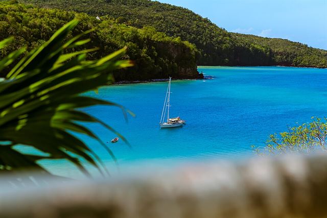 A sailing yacht at anchor in a turquoise bay