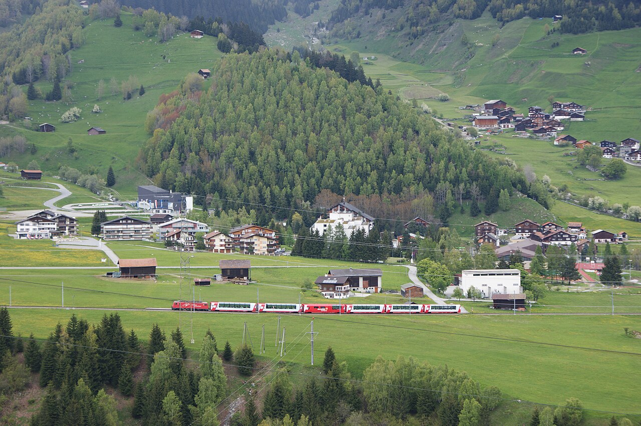The Glacier Express crossing a green valley below Disentis, Switzerland