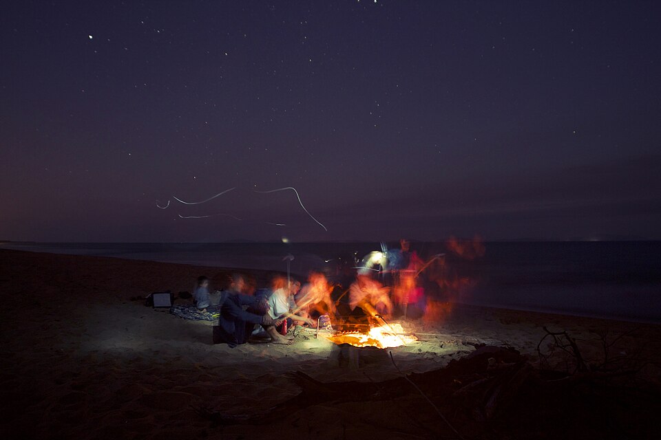 Friends round a campfire at night